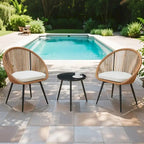 Ensemble repas décontracté pour balcon extérieur, composé d'une table basse ronde moderne anti-déversement, de deux chaises pivotantes en rotin et de coussins.